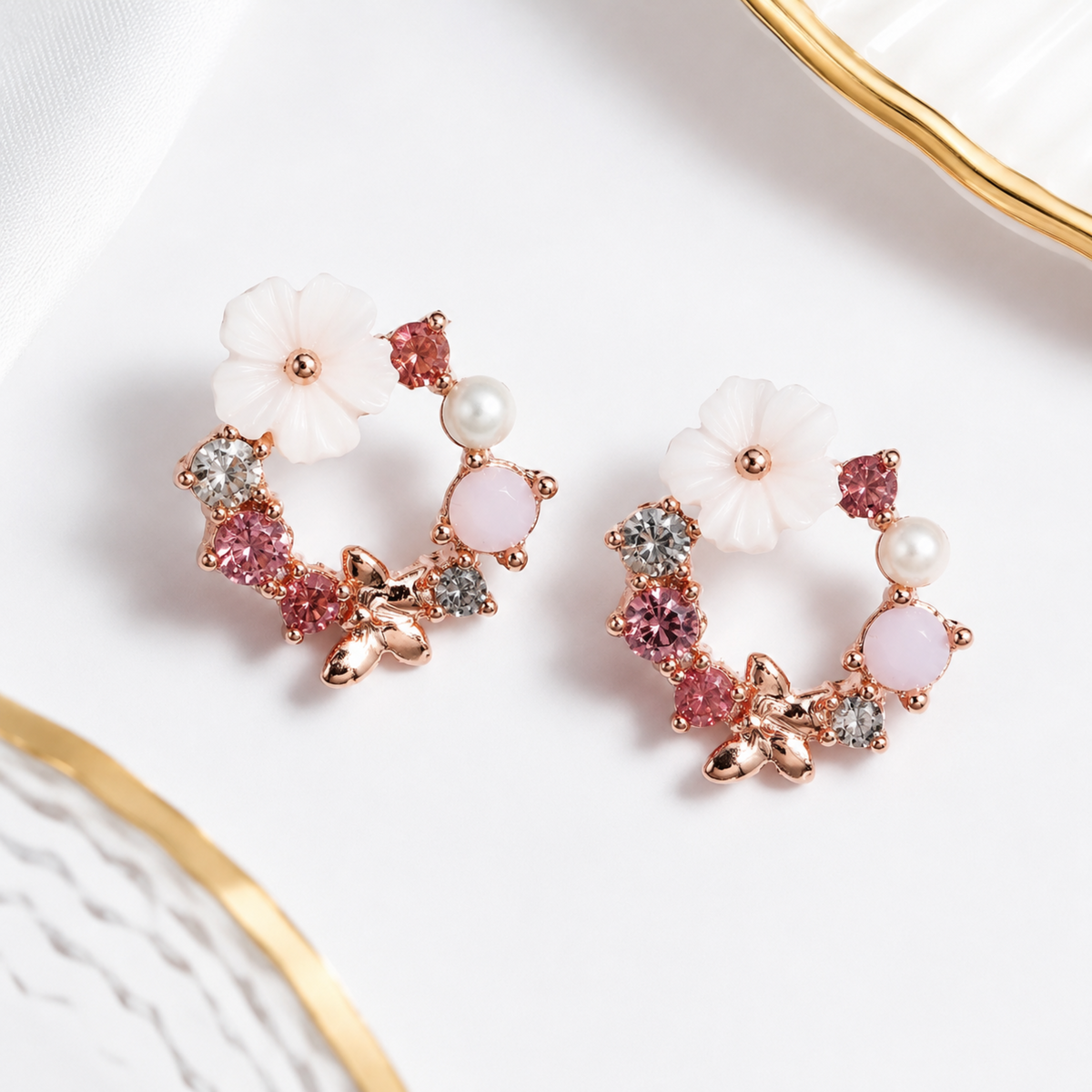 Pair of floral earrings with pink and white stones on a white background