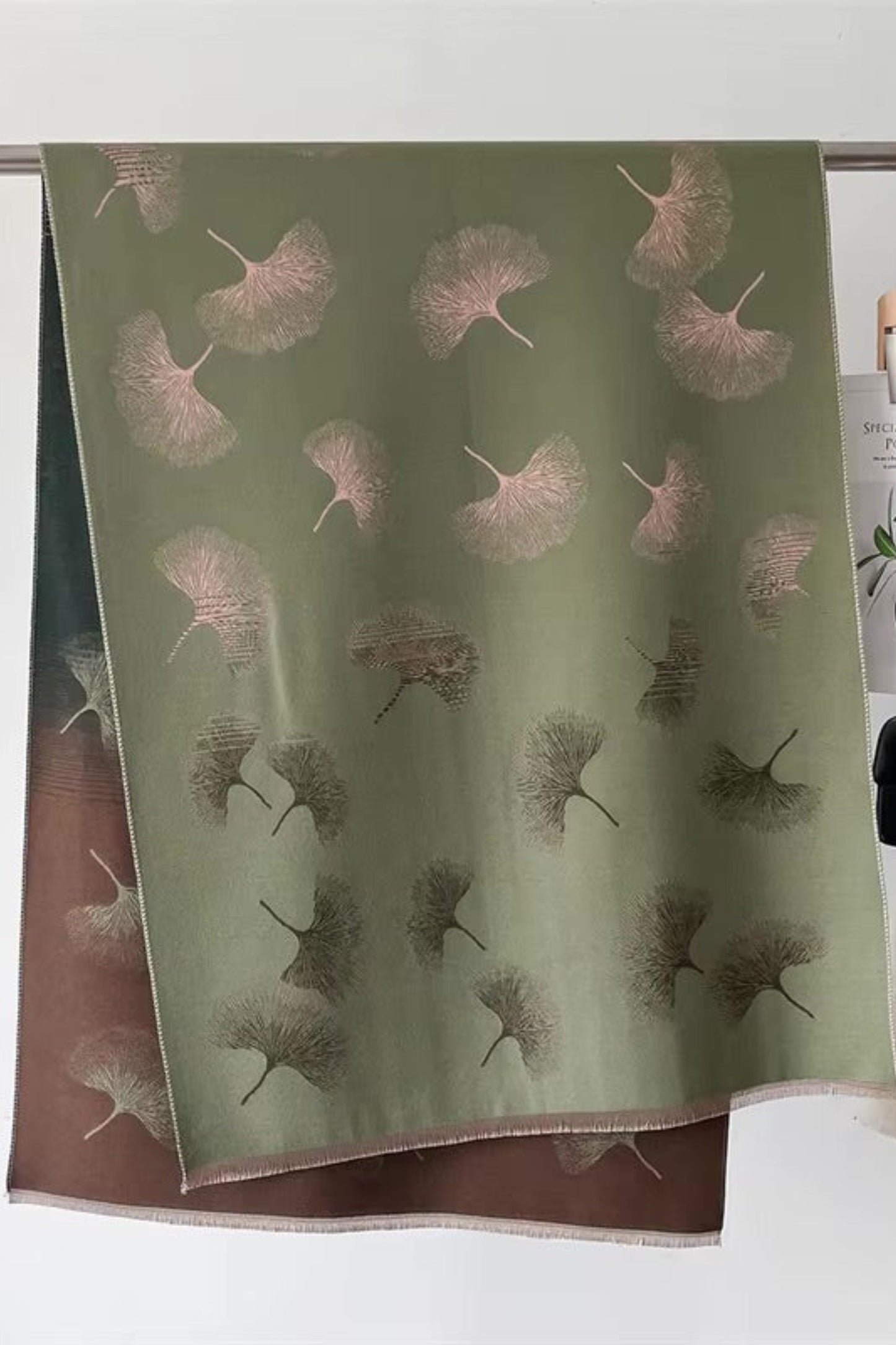 Green scarf with floral pattern hanging on a rack
