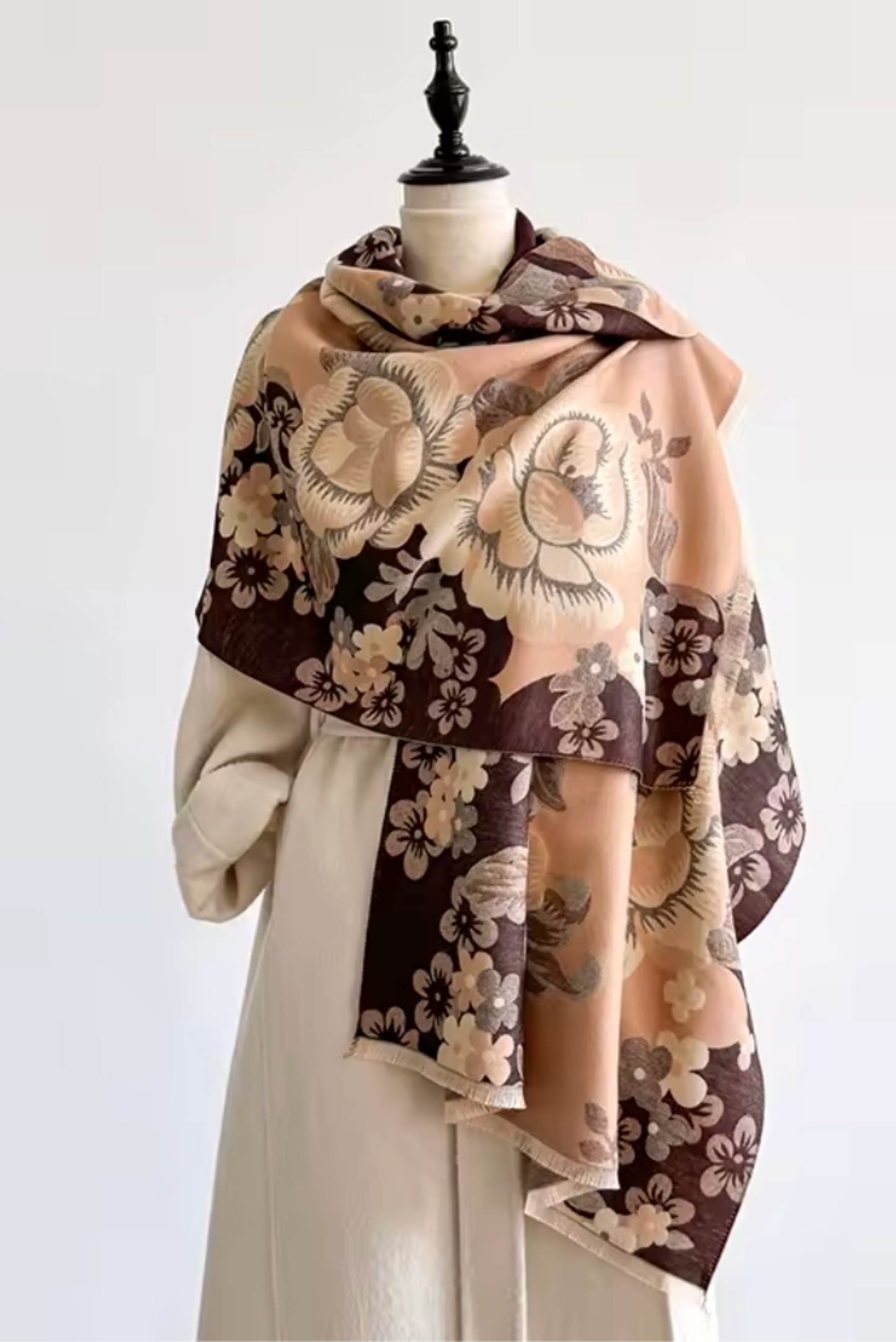 A beige and brown floral shawl draped over a cream-colored dress form against a plain white background.
