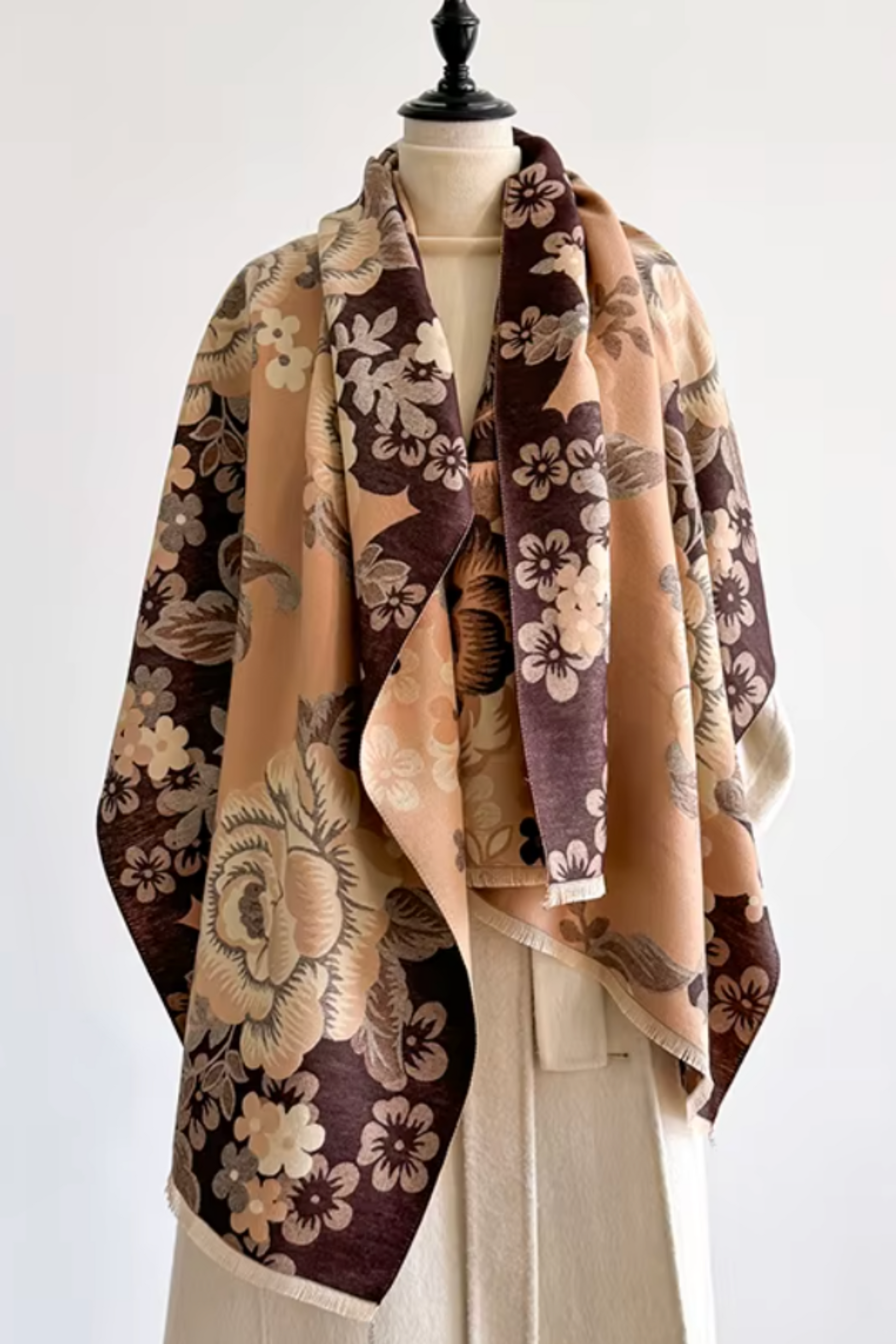 A floral shawl with a vintage Japanese-inspired pattern in beige, brown, and deep plum purple, draped over a cream-colored cardigan on a mannequin torso against a plain white background.