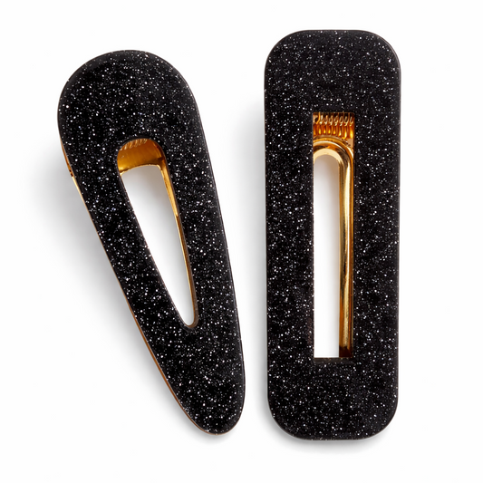 Black glittery hair clips with gold centers on a white background