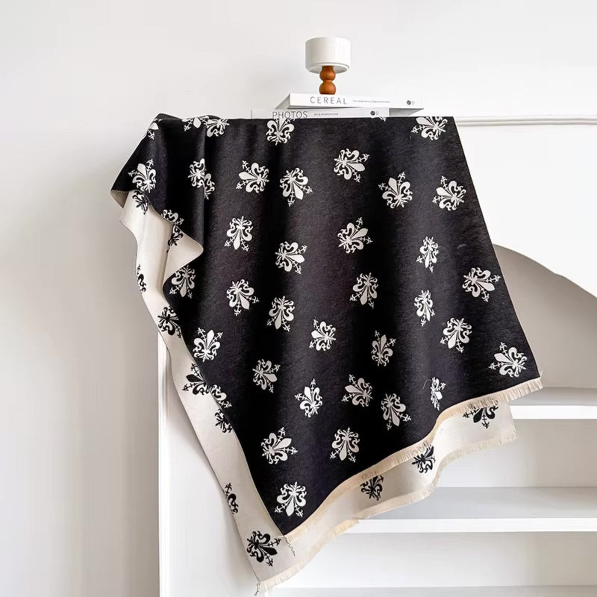 Black scarf with white floral patterns draped over a white surface