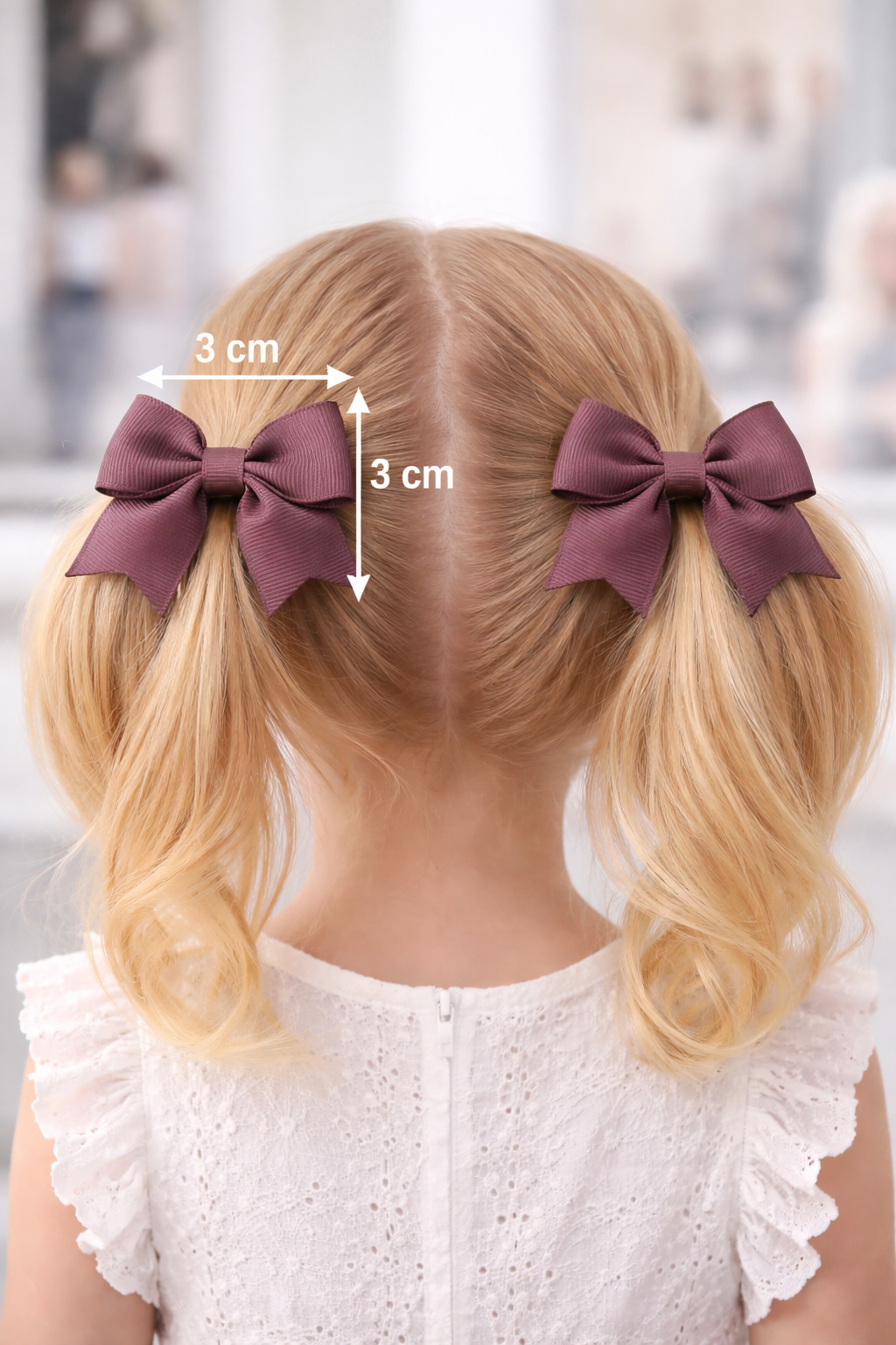 Child with blonde hair styled in pigtails wearing purple hair bows, with measurements indicated.