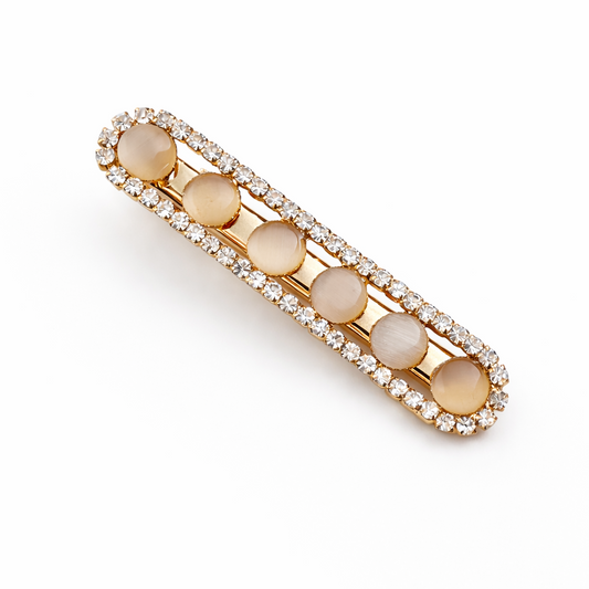 Gold hair barrette with beige stones on a white background