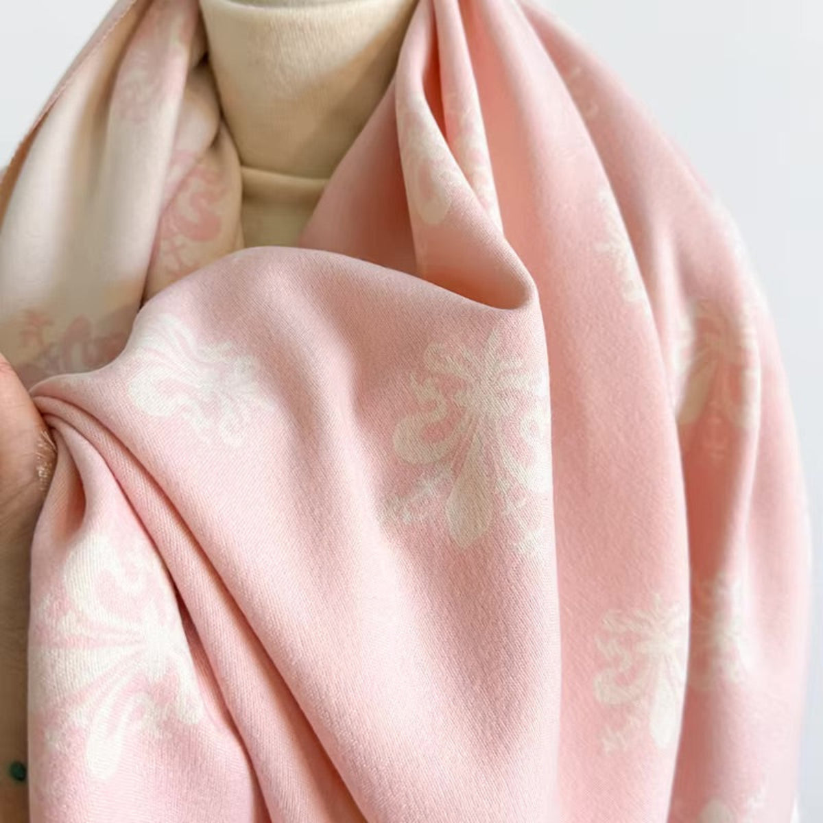 Close-up of a pink fabric with subtle patterns on a light background