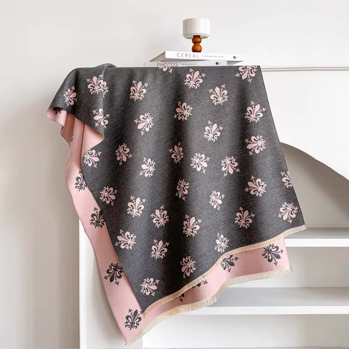 Dark gray scarf with floral patterns draped over a white surface