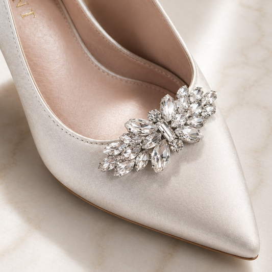 White pointed-toe shoe with a decorative crystal brooch on a light background