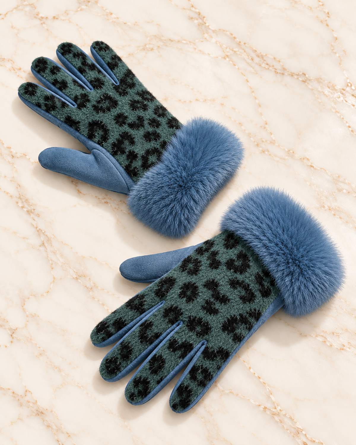 A pair of blue knit gloves with a black leopard print pattern and fluffy blue faux-fur cuffs, displayed on a beige marble background.