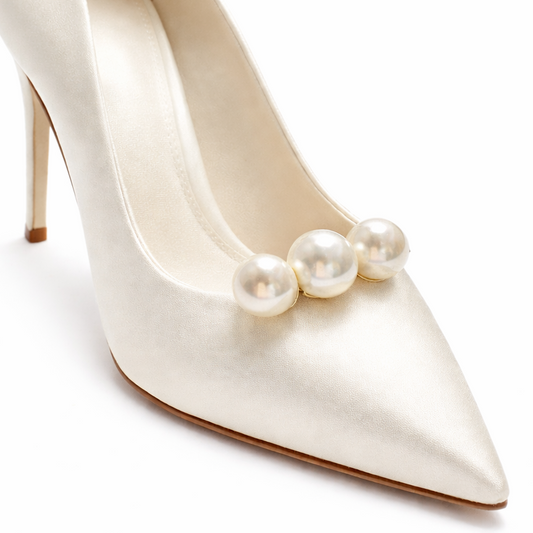 White high-heeled shoe with pearl embellishments on a white background