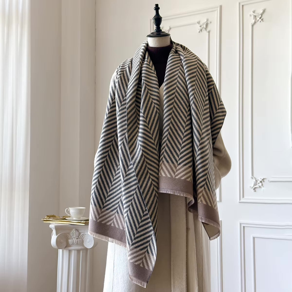 Mannequin wearing a patterned scarf in a room with white walls and a small table.