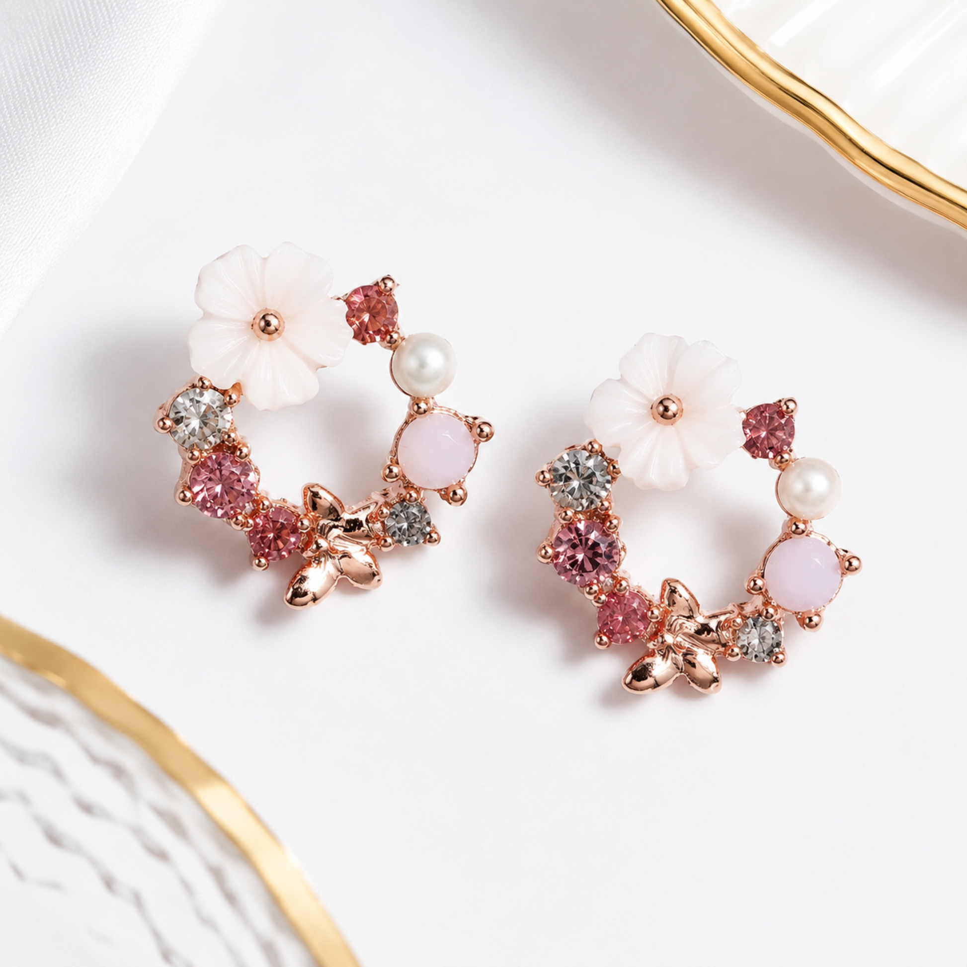 Pair of floral earrings with pink and white stones on a white background