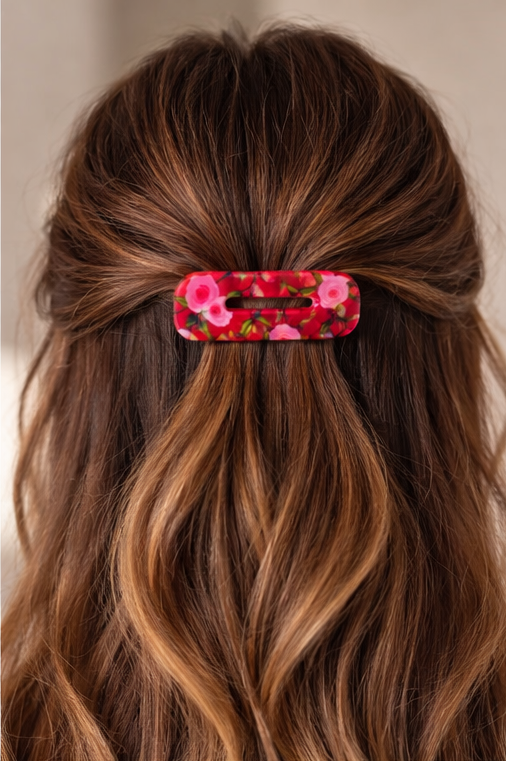 Close-up of brown hair with a floral hair clip against a neutral background