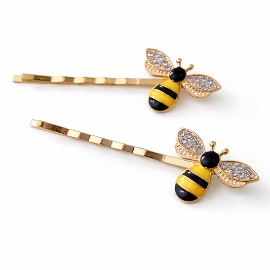 Two bee-shaped hair pins with gold bodies and black and yellow details on a white background