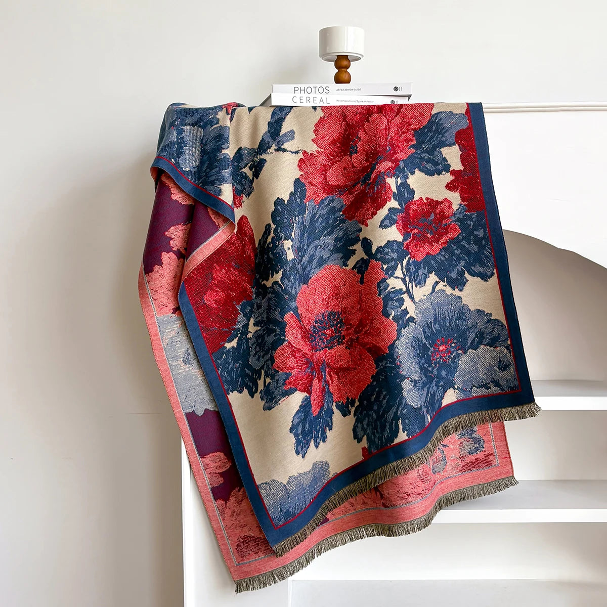 Floral patterned blanket draped over a chair with a white background
