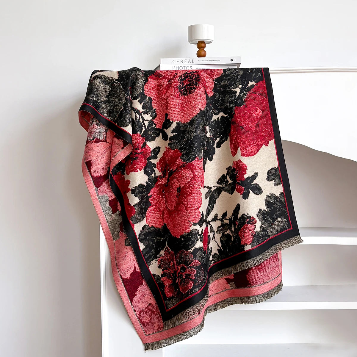 Floral patterned blanket draped over a white surface with a minimal background