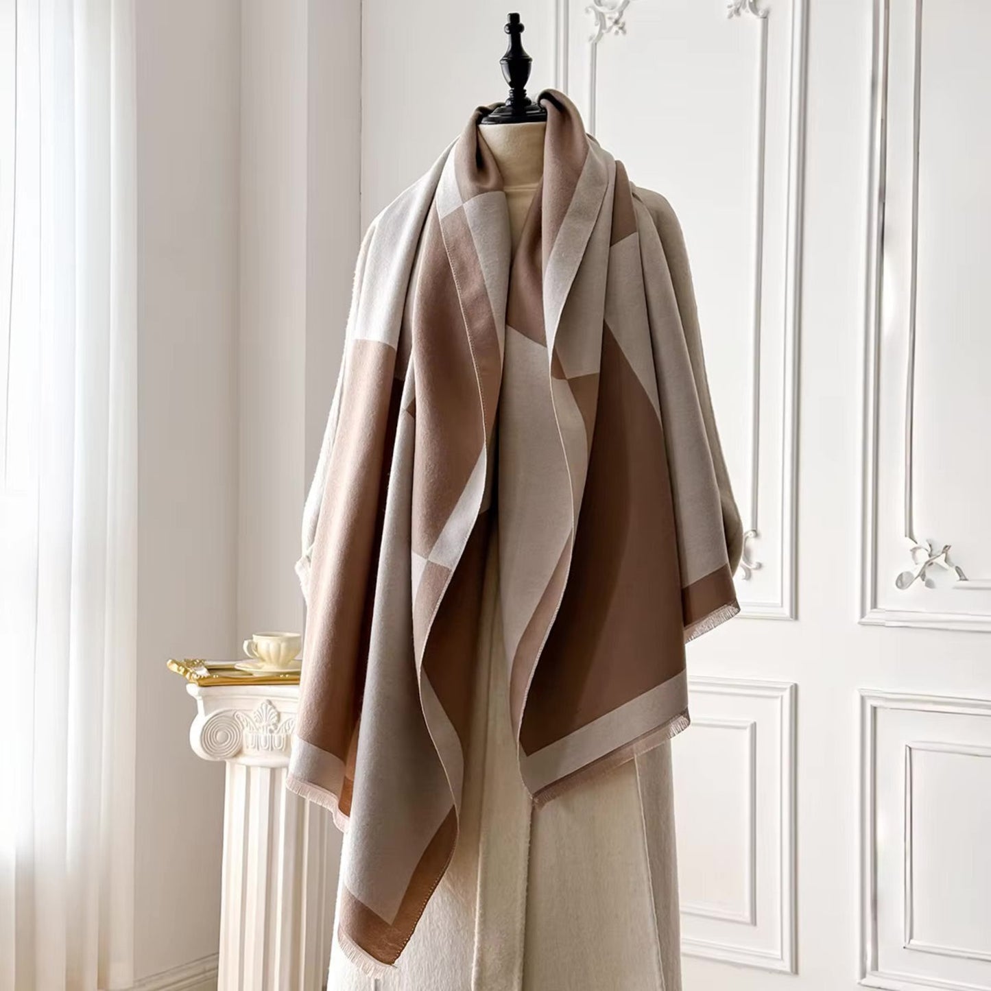 Beige and brown patterned scarf on a mannequin against a white paneled wall.