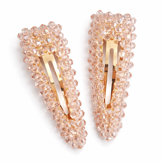 Pair of decorative hair clips with pink bead detailing on a white background