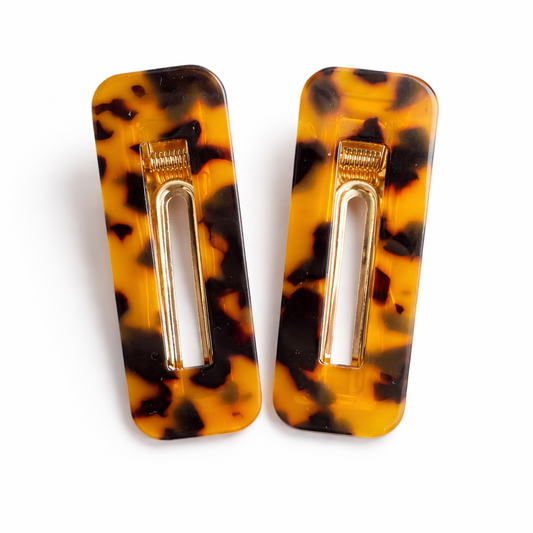 Tortoiseshell hair clips with gold barrettes on a white background