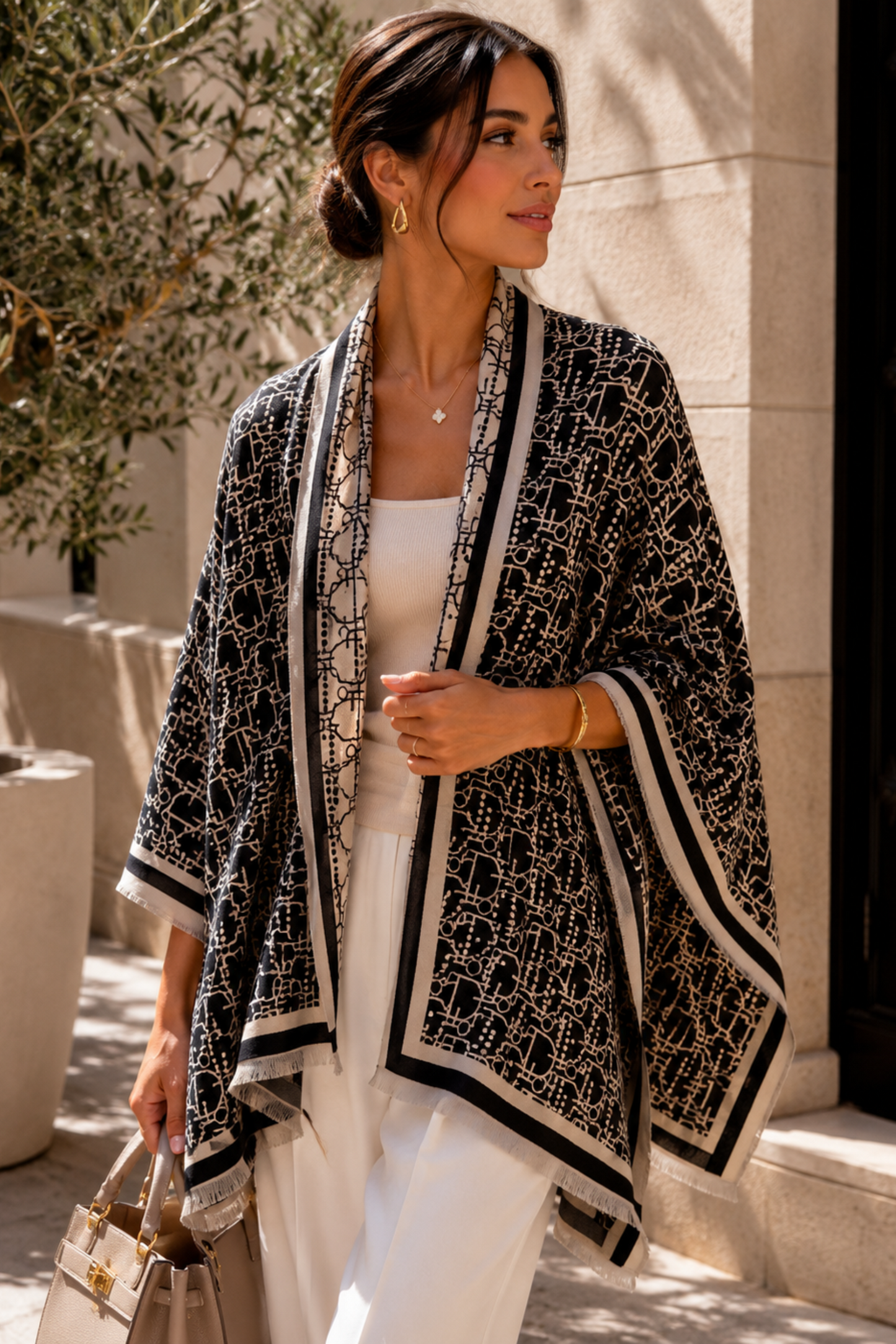 Woman wearing a black and white patterned cardigan in an outdoor setting.