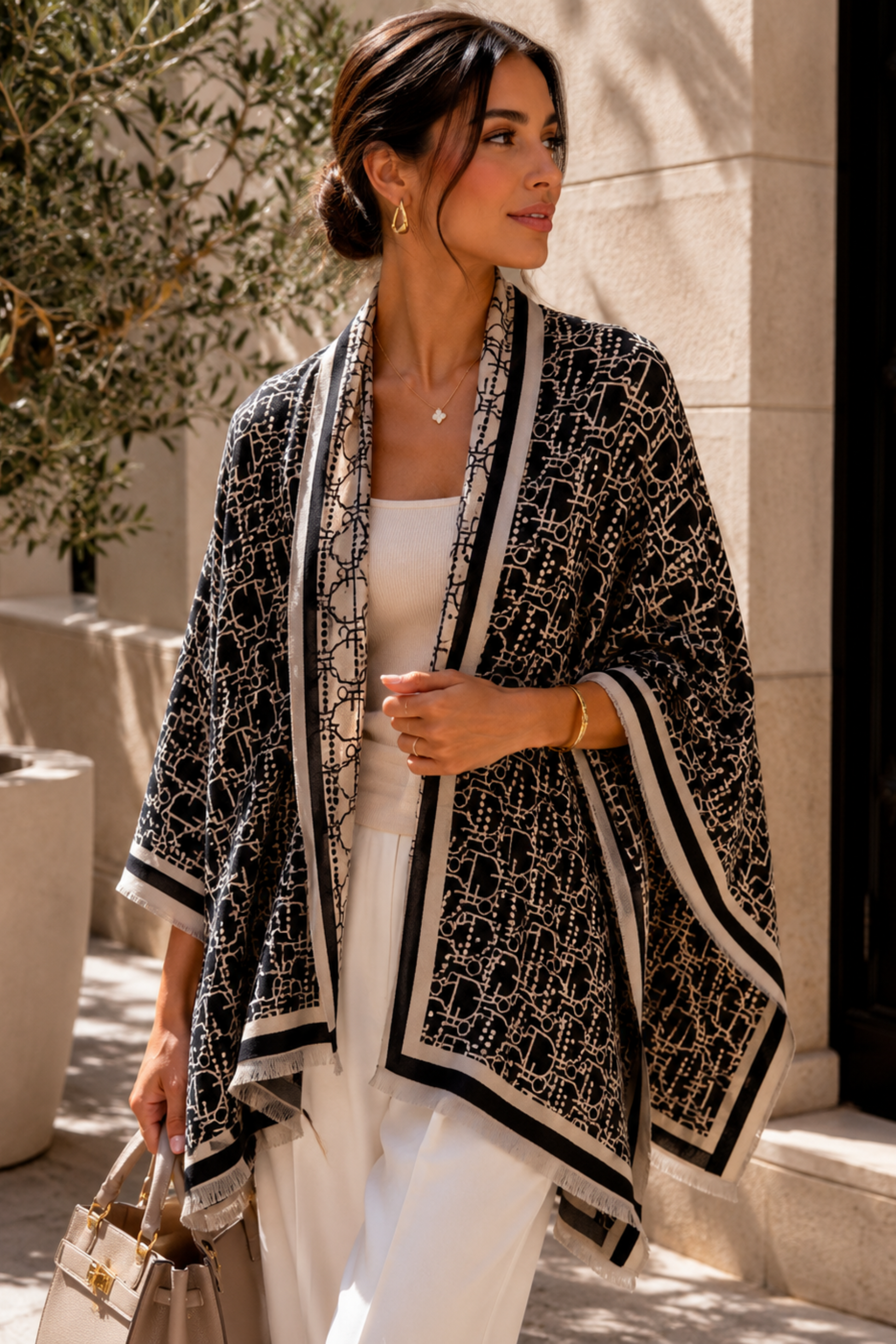 Woman wearing a black and white patterned cardigan in an outdoor setting.
