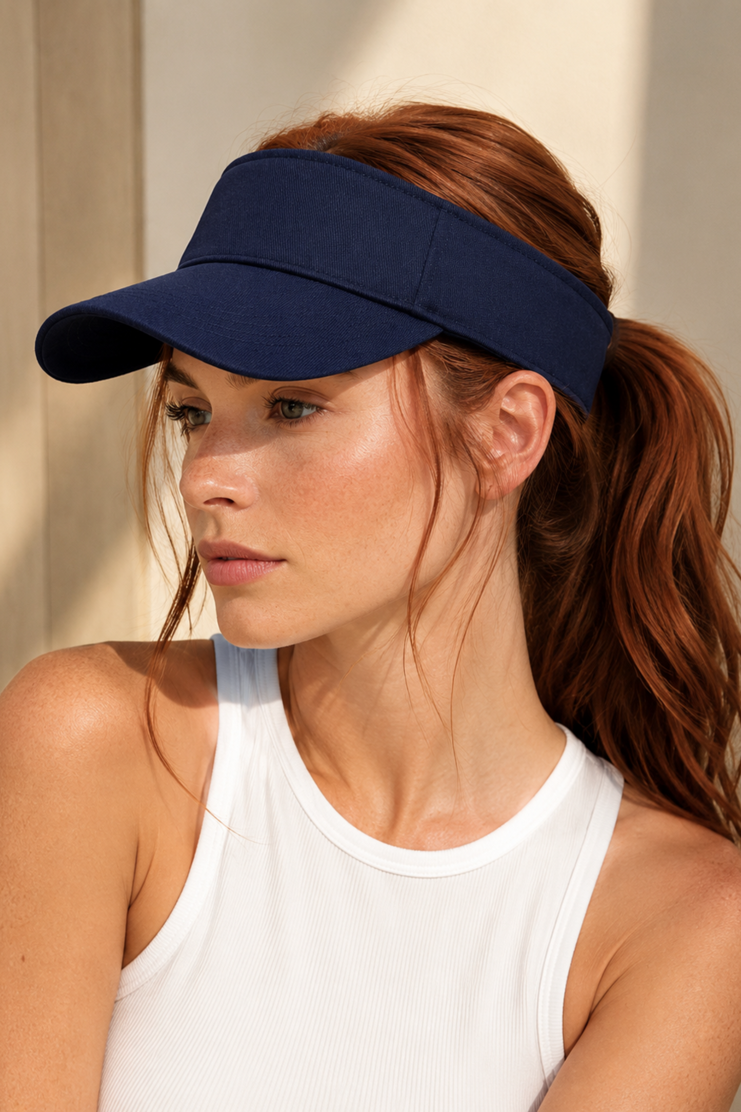 Woman wearing a navy blue visor with a neutral background