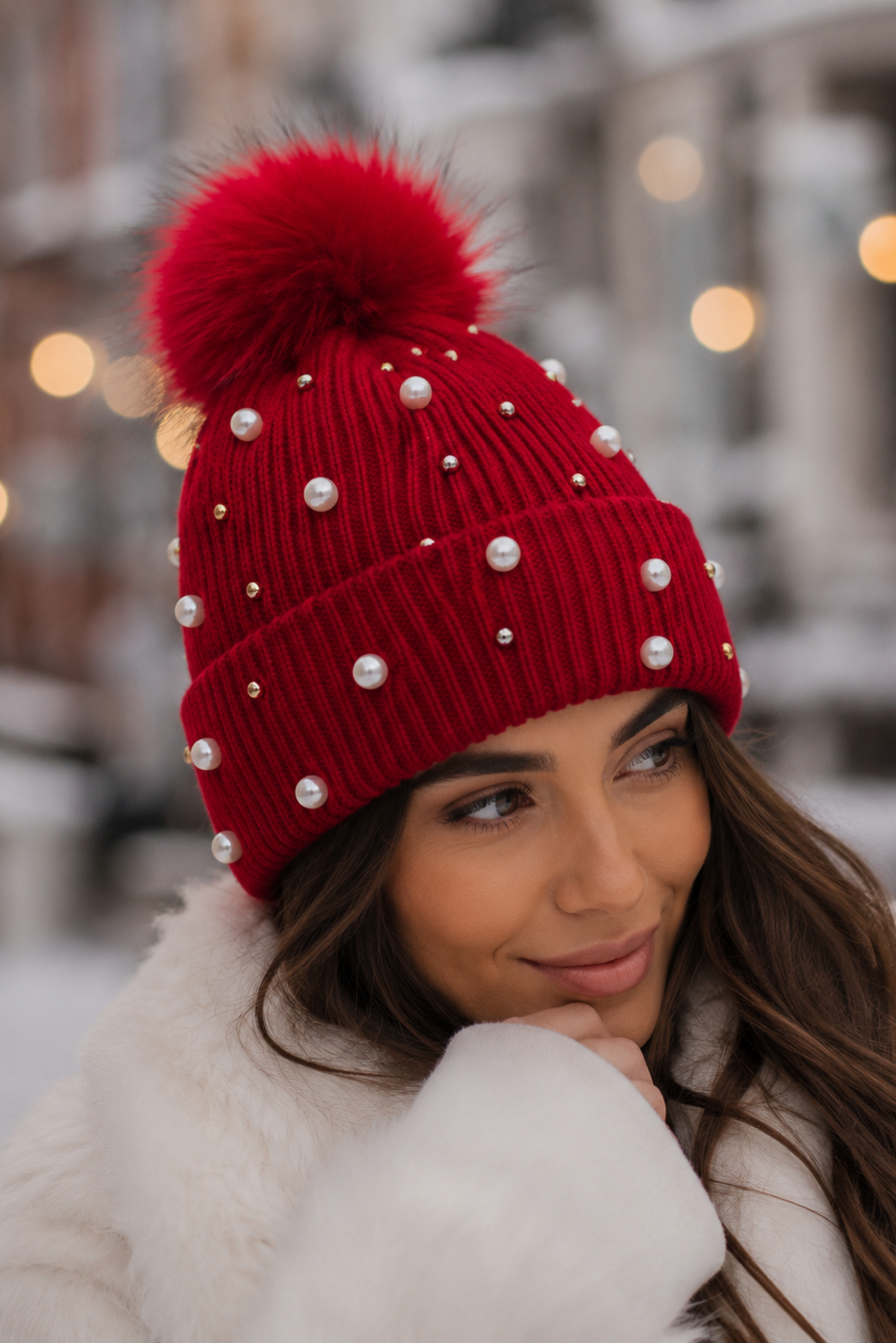 Woman wearing a red beanie with white pearls in an outdoor setting