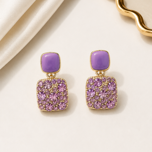 Purple earrings with gold accents on a beige fabric background