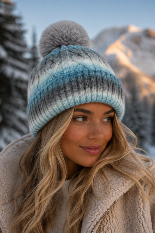 Woman wearing a striped knit beanie with a pom-pom in a snowy mountain landscape