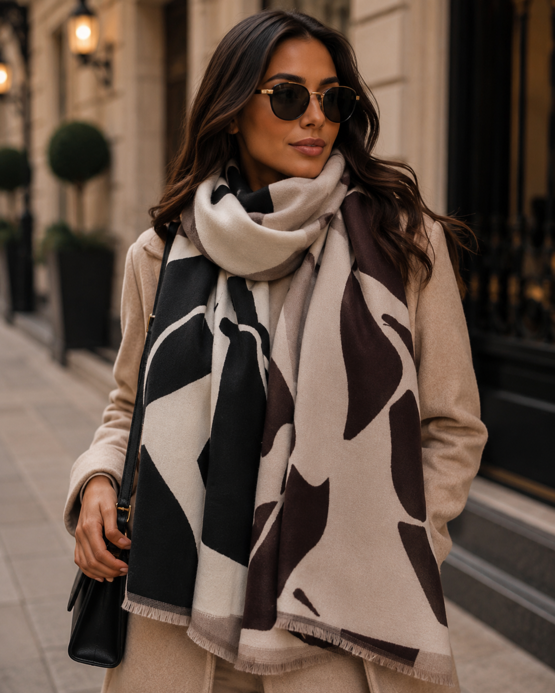 Woman wearing a patterned scarf and sunglasses on a city street.