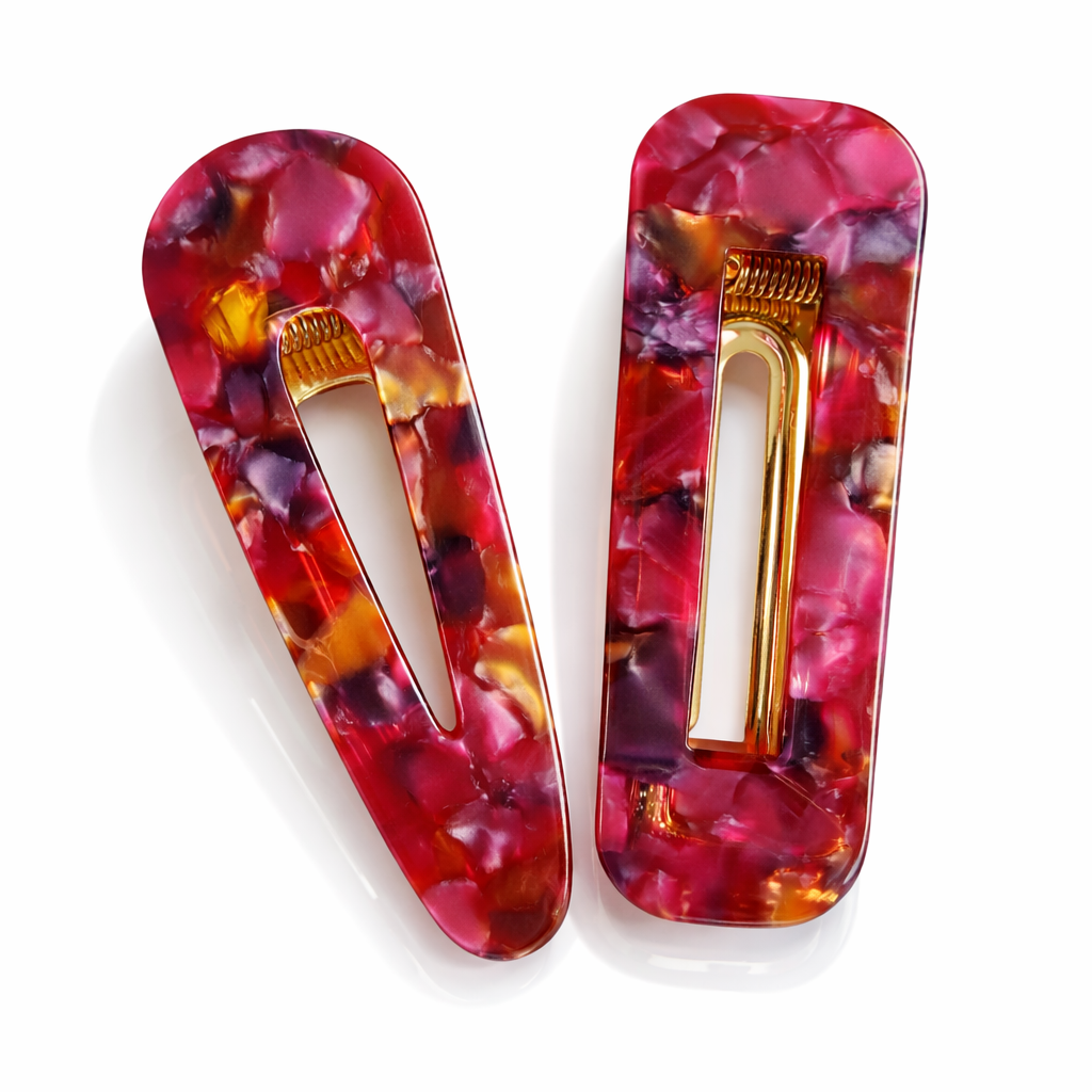 Two colorful hair clips with gold centers on a white background