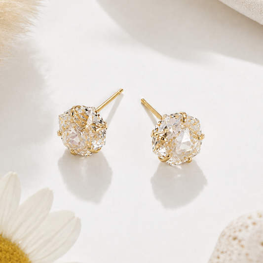 Gold earrings on a white surface with a daisy flower
