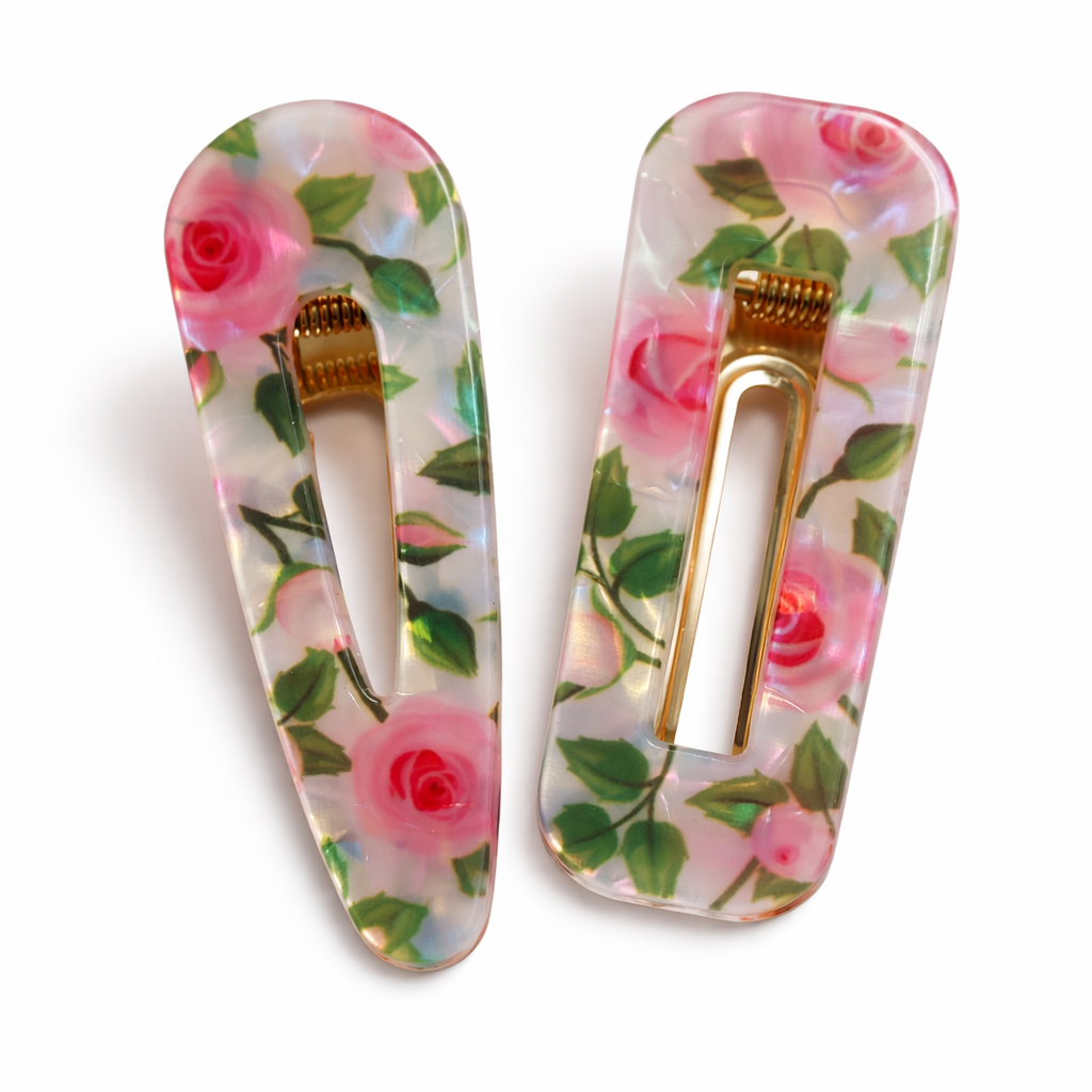 Two floral hair clips with pink roses and green leaves on a white background