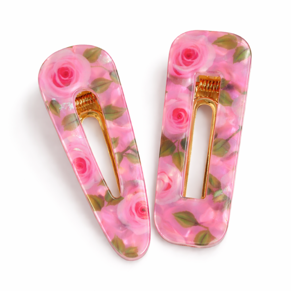 Two floral hair clips with pink roses on a white background