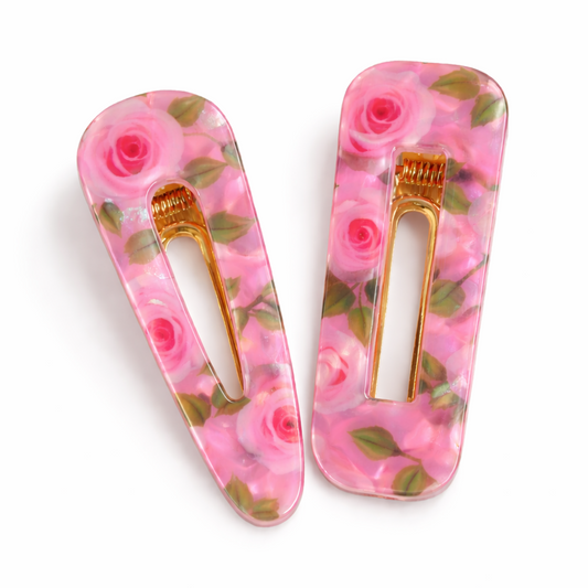Two floral hair clips with pink roses on a white background