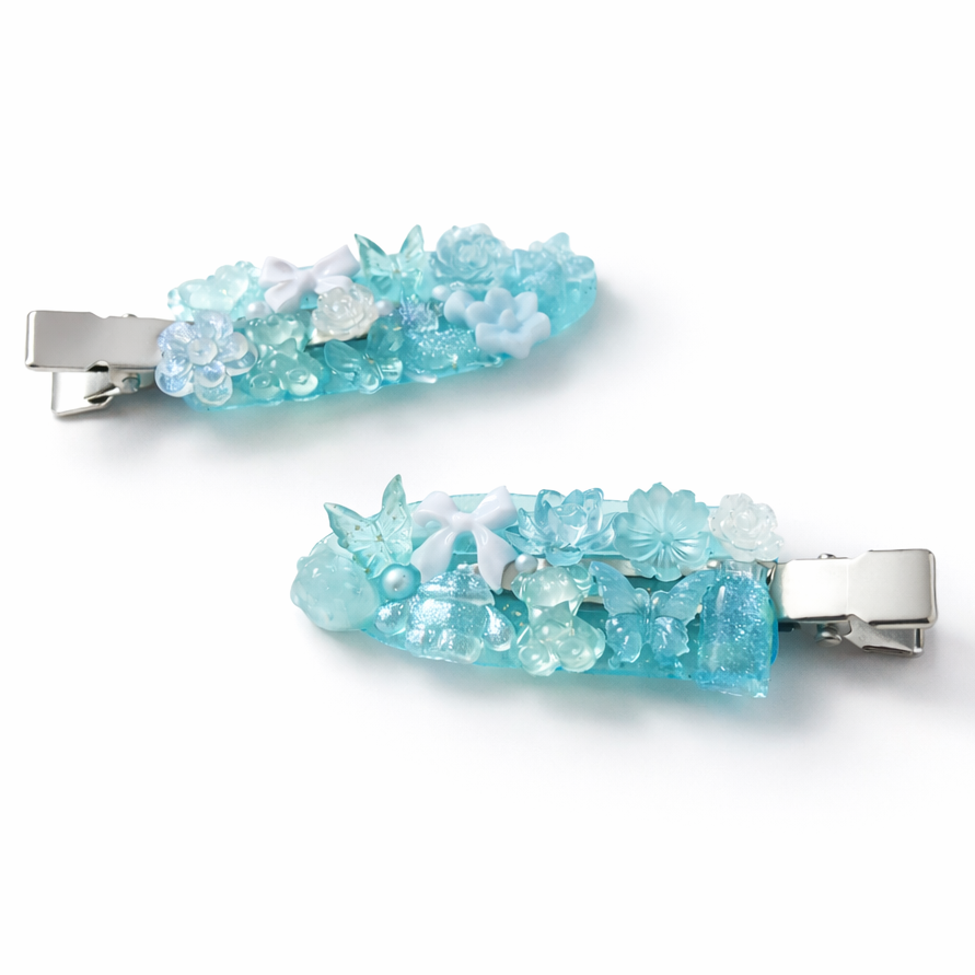 Two decorative hair clips with blue and silver design on a white background