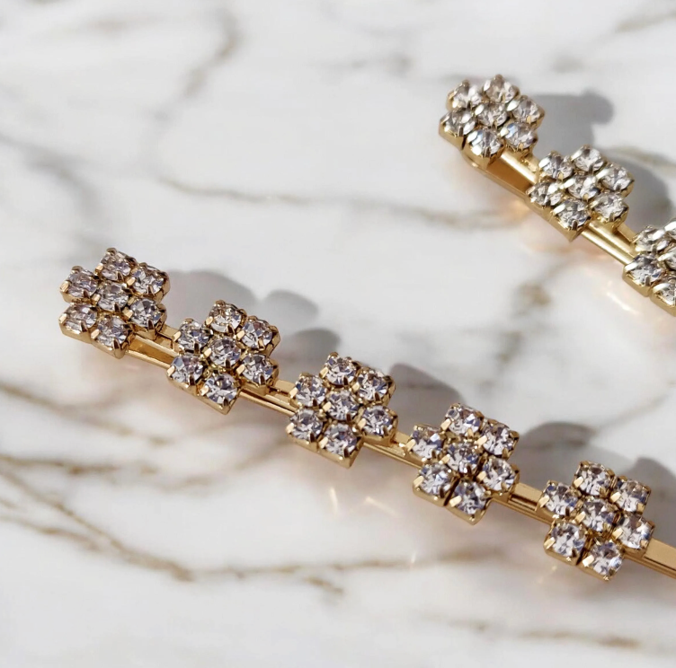 Gold hair pins with crystal embellishments on a marble background