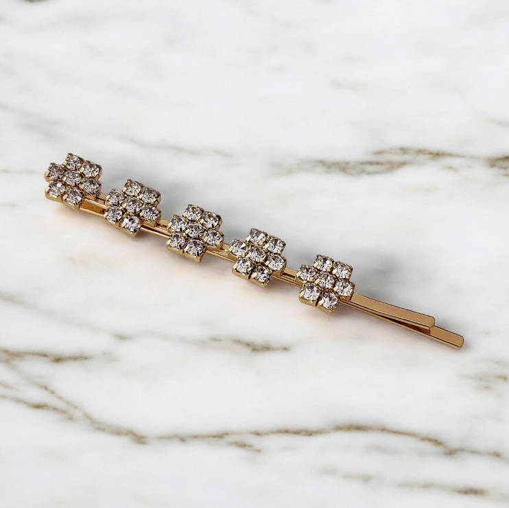 Gold hairpin with floral designs on a marble background