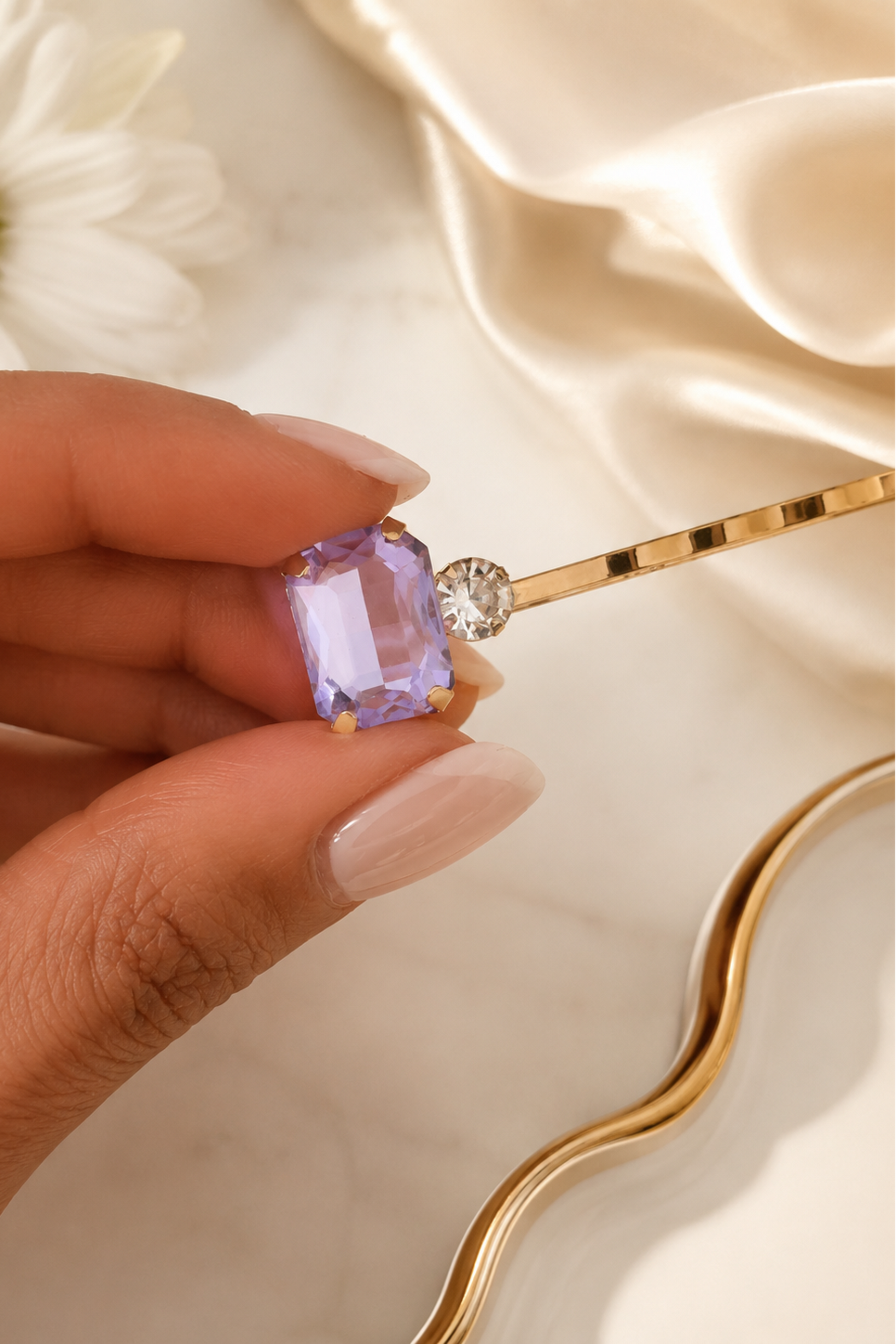 Close-up of a lilac crystal gold hair slide with a clear rhinestone detail, shown held in hand, an elegant women’s bobby pin hair accessory for weddings, bridesmaids, parties and occasion styling.