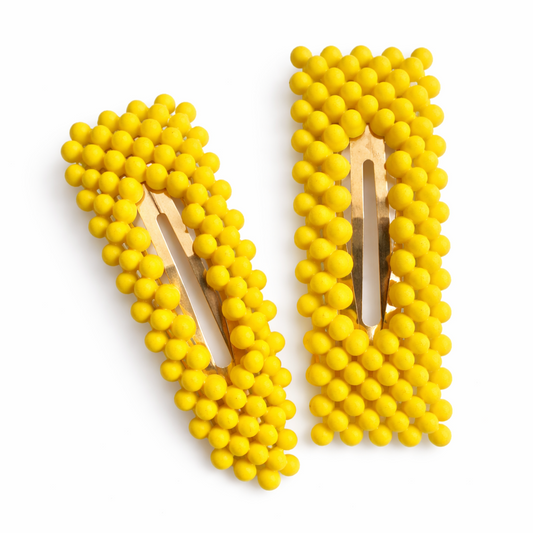 Yellow beaded hair clips on a white background