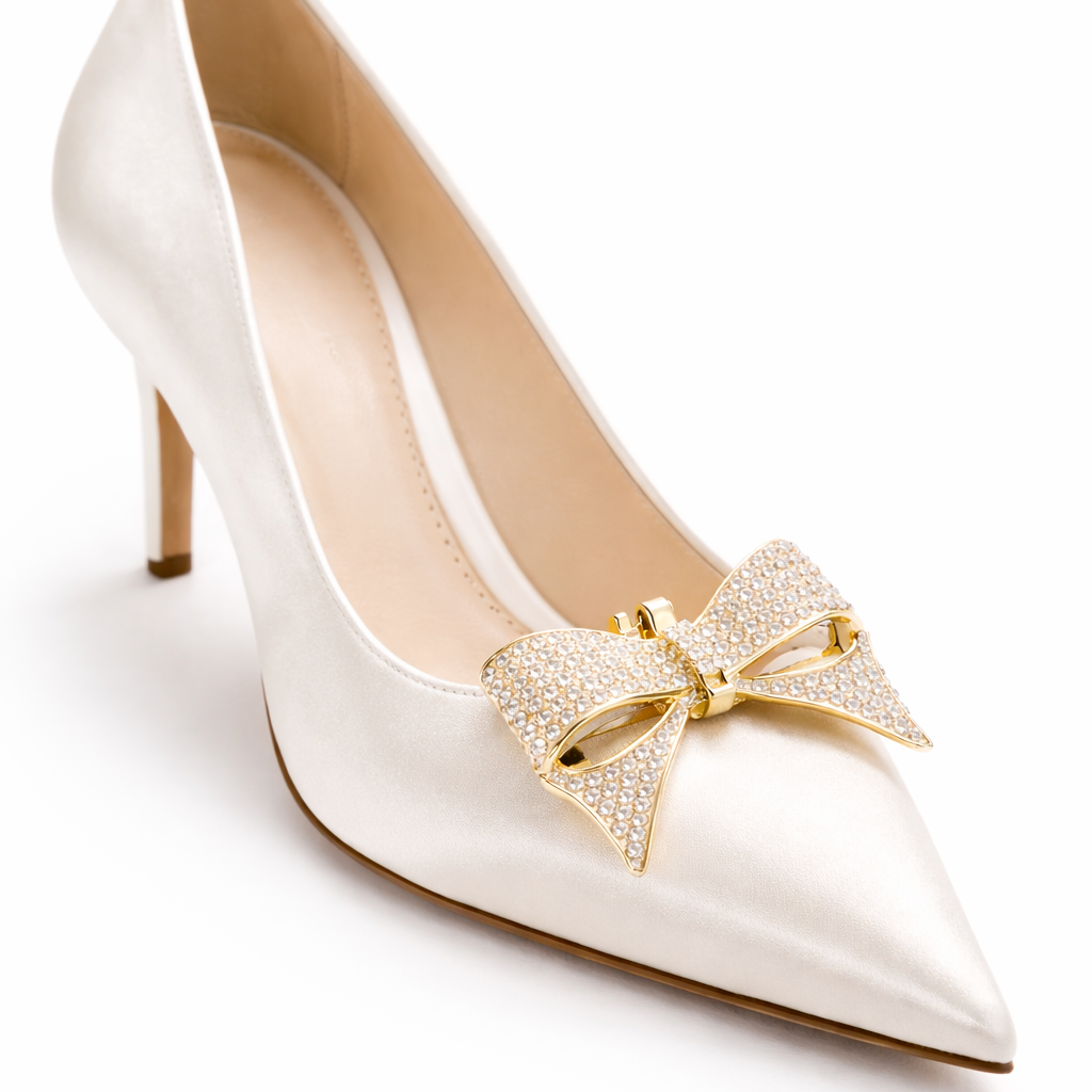 White high-heeled shoe with a gold bow accessory on a white background