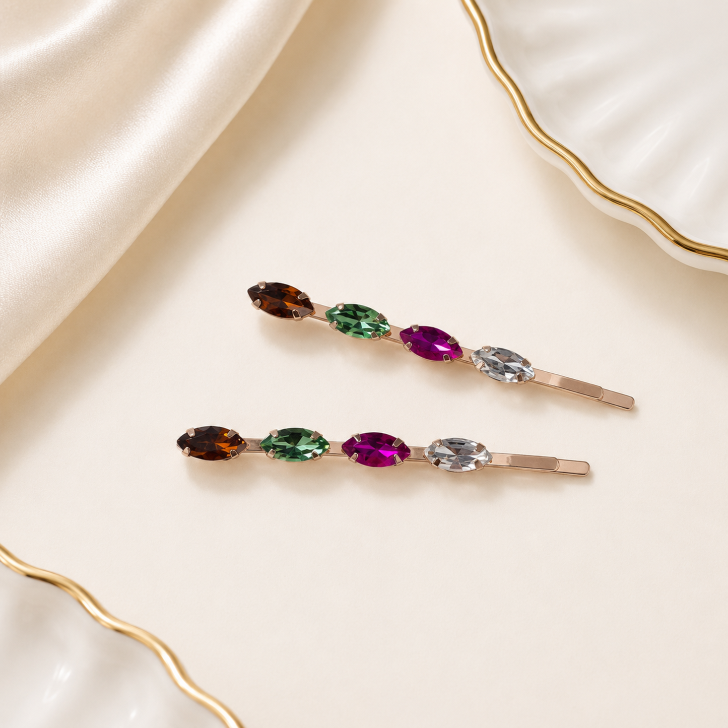 Two hair clips with multicolored gemstones on a beige fabric background
