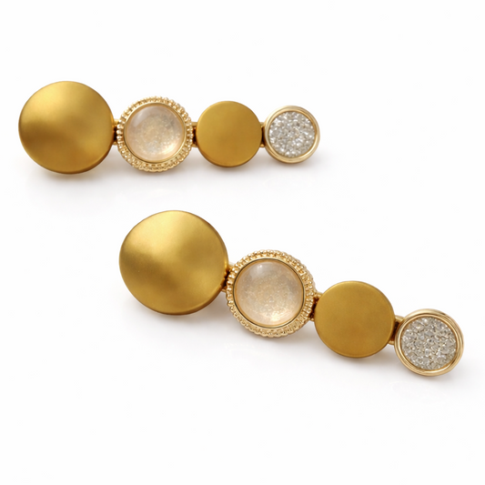 Pair of gold earrings with round and diamond-studded elements on a white background