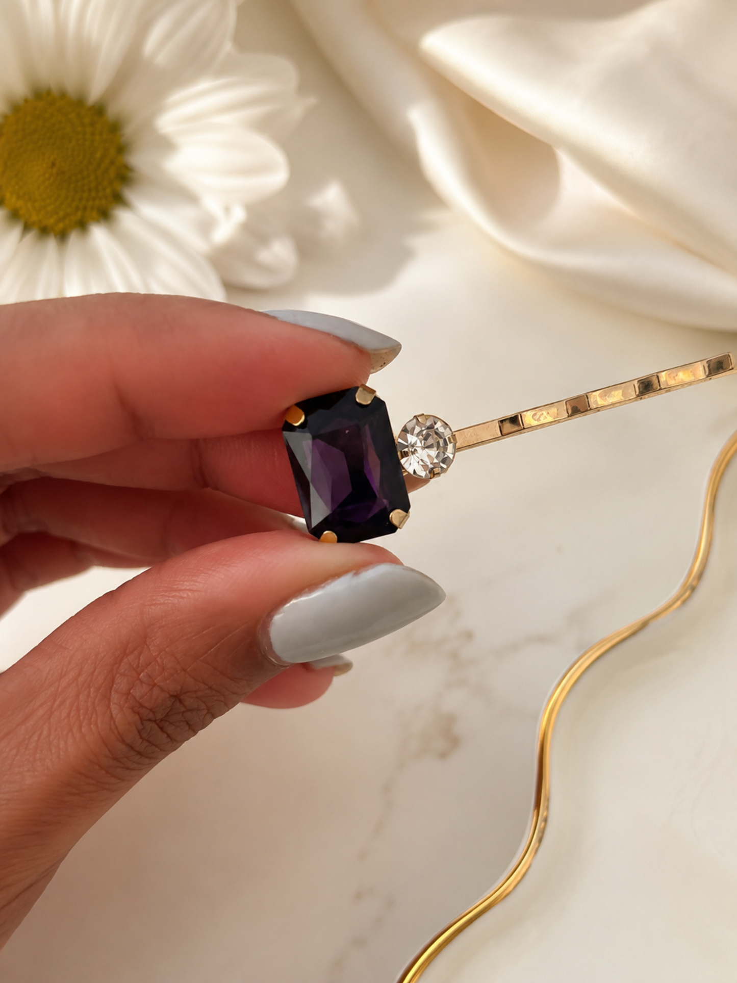 Close-up of a gold hair slide with a deep purple rectangular crystal and clear rhinestone detail, an elegant women’s hair accessory for weddings, parties, bridesmaid looks and evening styling.