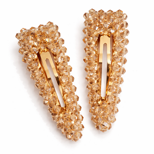 Pair of gold hair clips with crystal-like embellishments on a white background