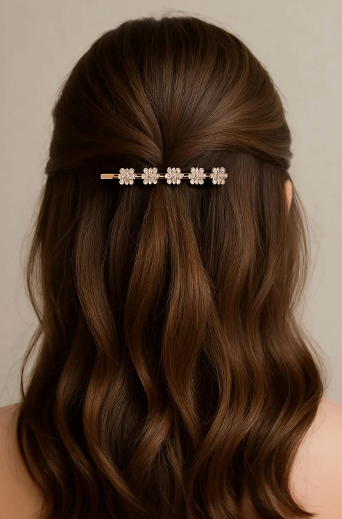 Woman with wavy brown hair wearing a decorative hairpin against a neutral background