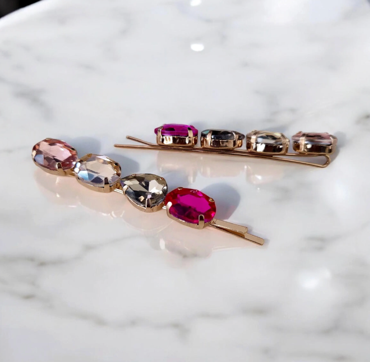 Two hair pins with gemstones on a marble surface