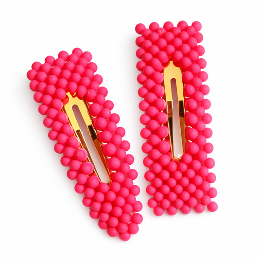 Pair of pink beaded hair clips with gold centers on a white background