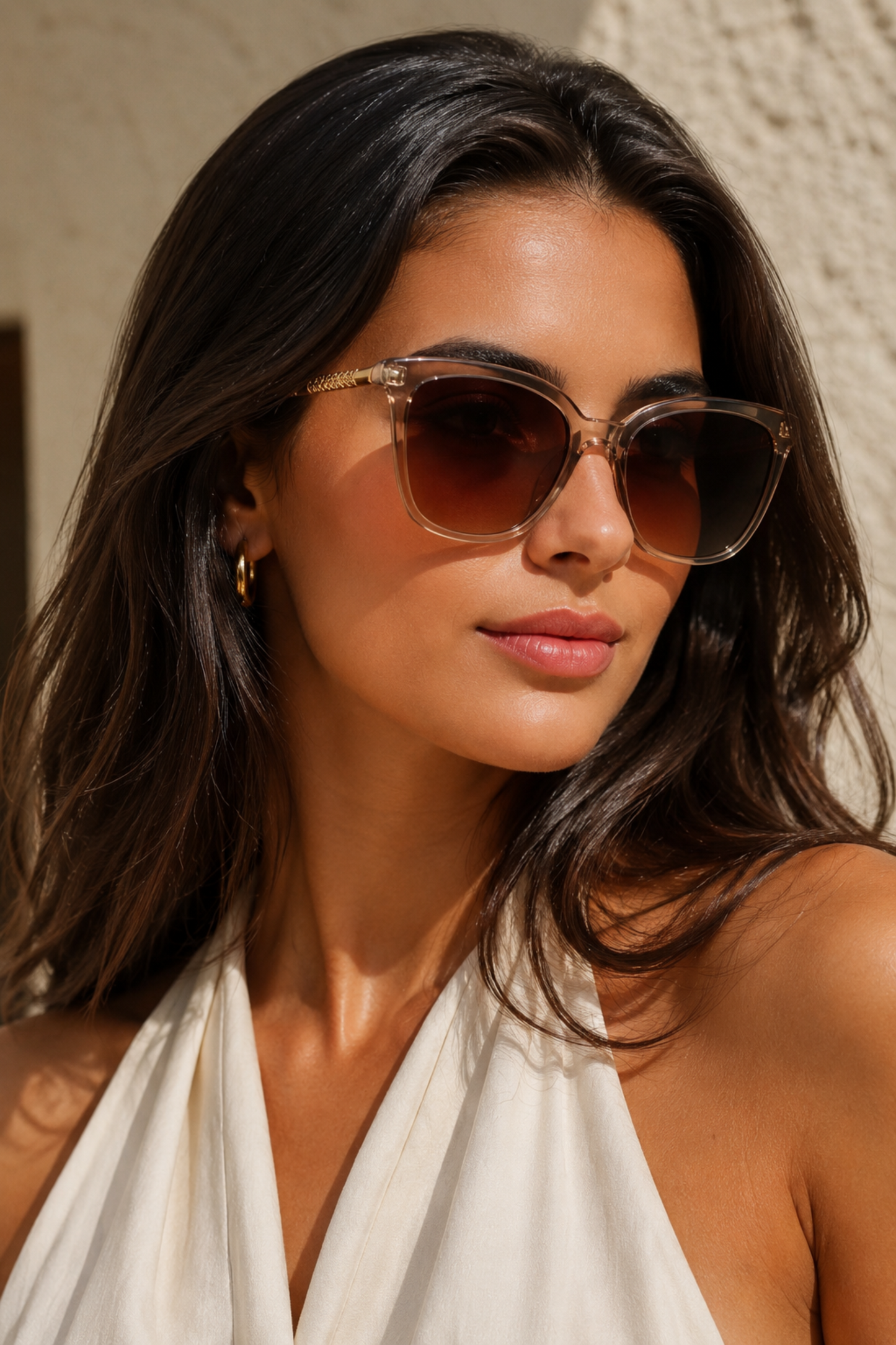 Woman wearing sunglasses and a white top against a neutral background