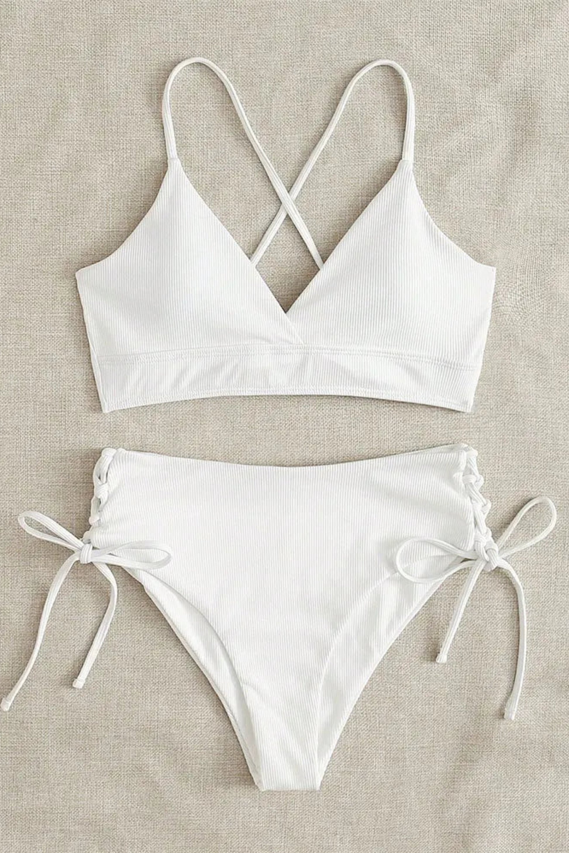 White bikini set on a beige fabric background